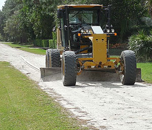 Grading equipment performing maintenance on dirt road in the District